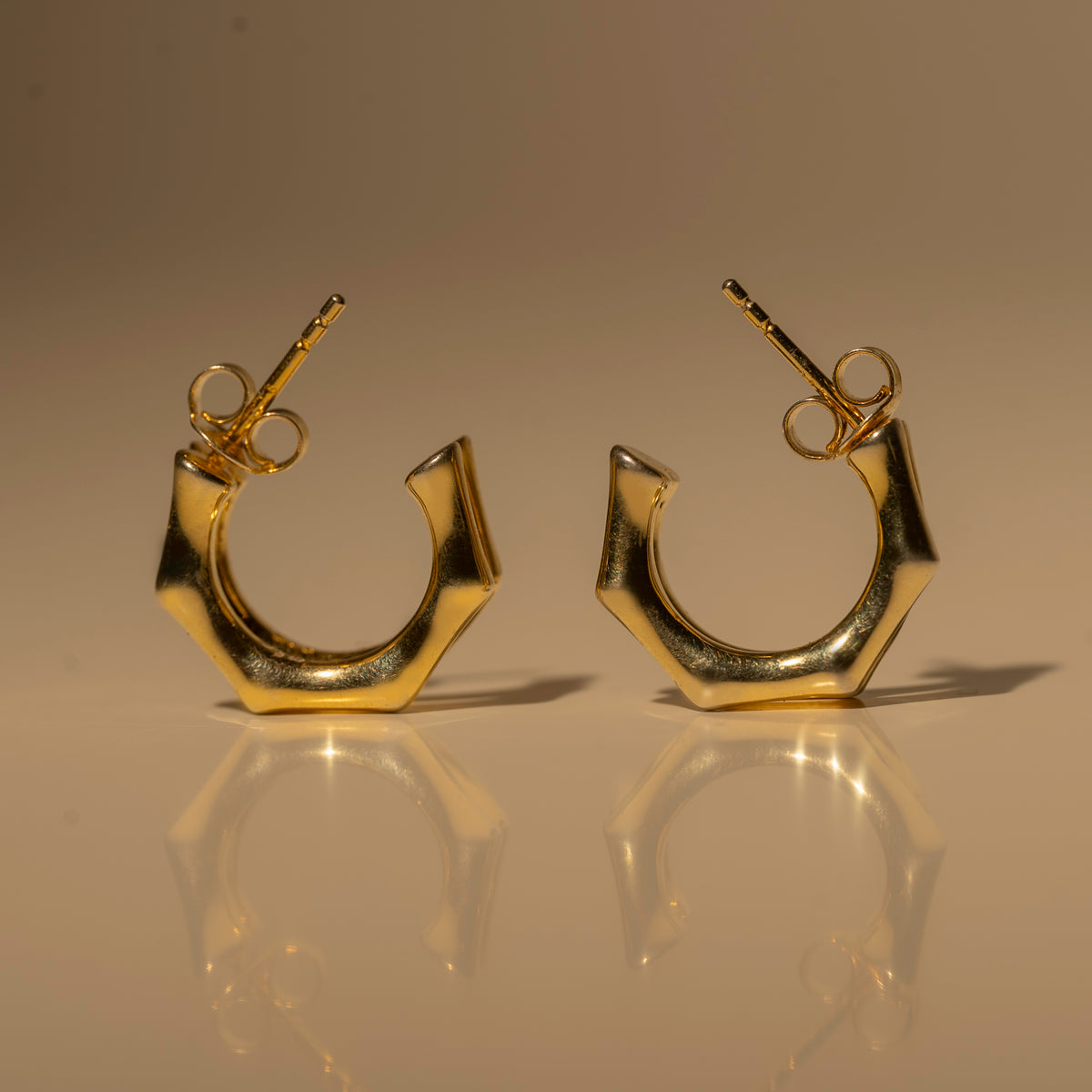 Milk & Rose Eve Hoops in a gold tone, showing their angular open curves and butterfly backs from the front.