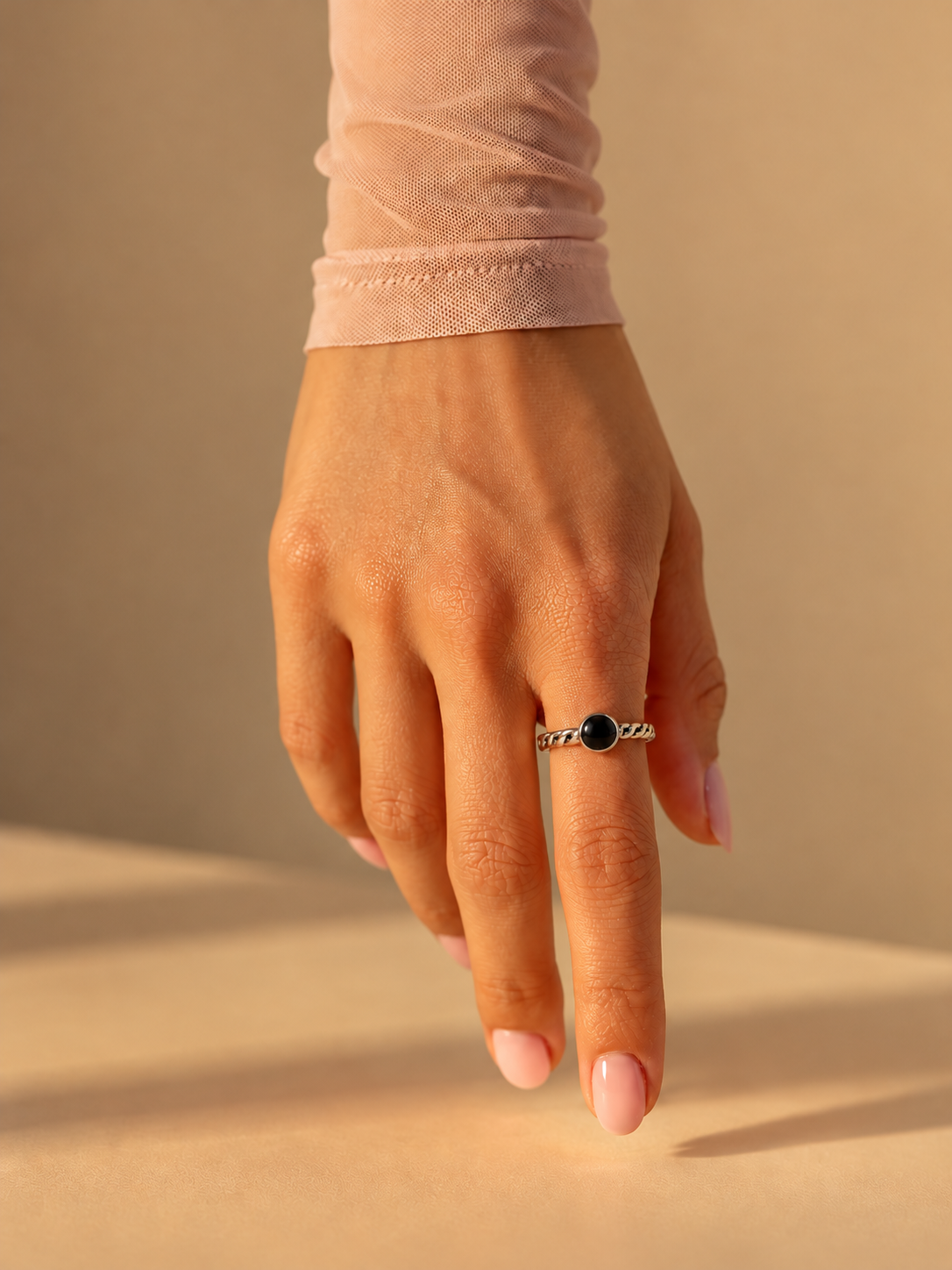 Ribbon Onyx Ring worn on a hand, sterling silver twisted band with a round black onyx stone