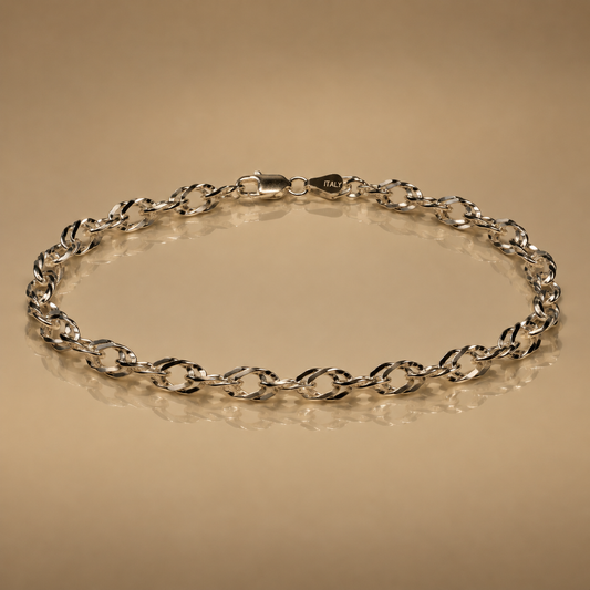 Twisty Chain, sterling silver twisted-link chain with lobster clasp, laid in a loop on a beige background