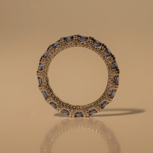 Glamband Ring with blue-purple stones and small clear accents, standing upright on a beige surface