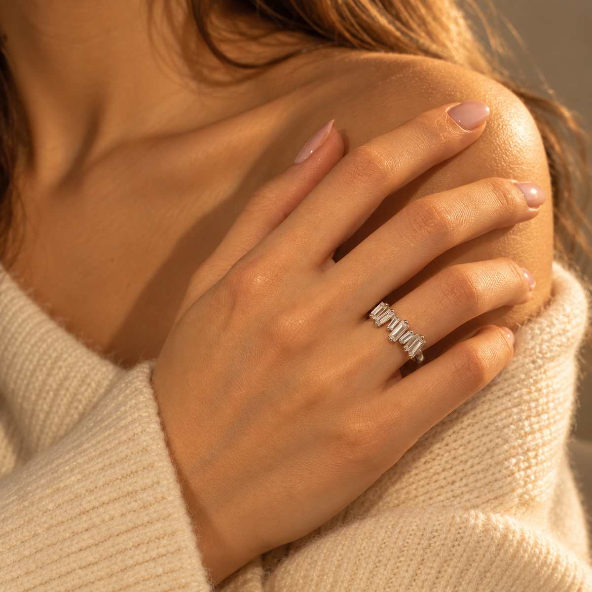 Milk & Rose Ice Ring worn on a hand resting against a shoulder, with clear rectangular stones beside a cream knit sweater in warm light.
