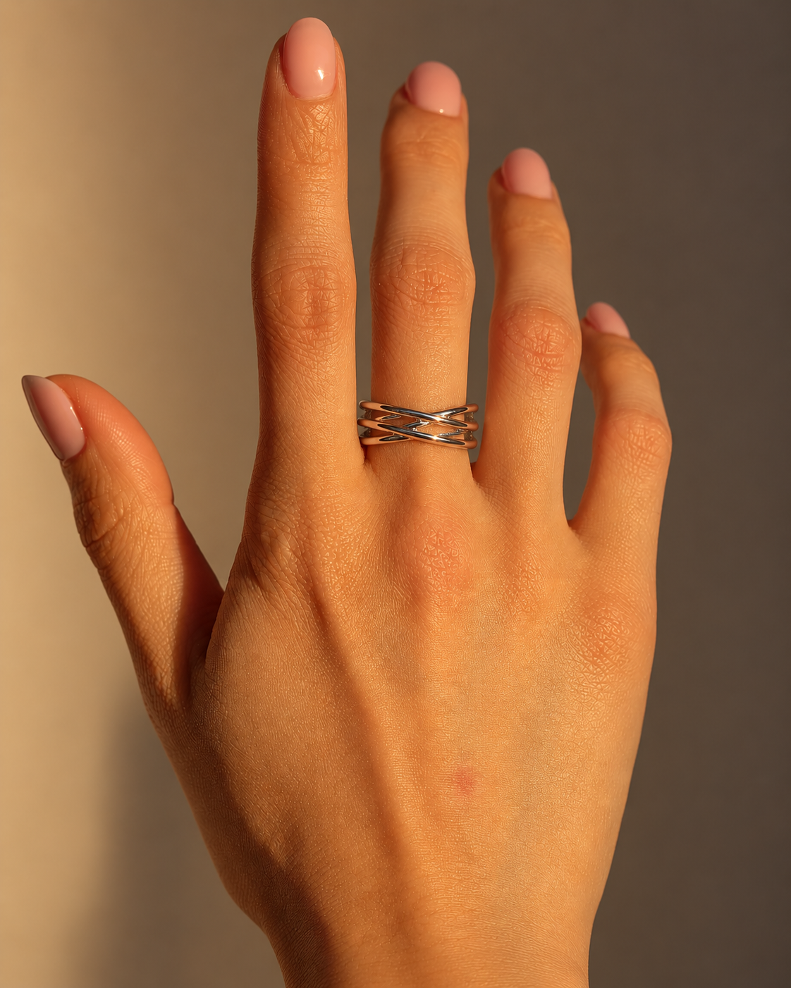 Milk & Rose Dainty Forest Ring worn on a middle finger, showing slim silver-tone bands crossing in an airy layered pattern against a warm beige background.